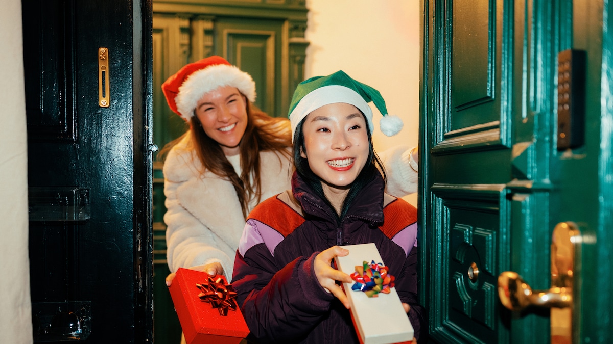 Zwei Frauen mit Weihnachtsmützen und Geschenken