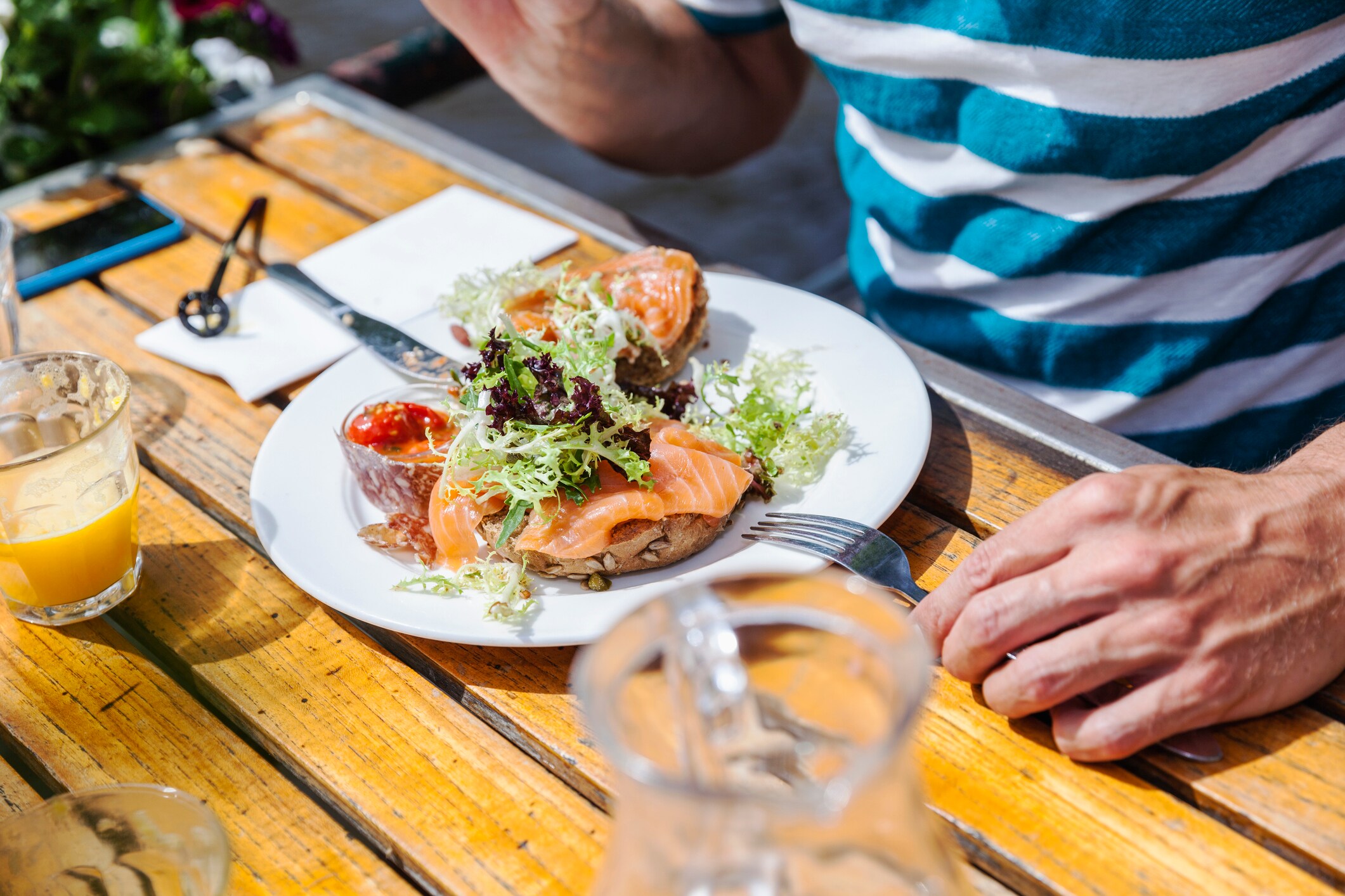 Herr isst Lachs auf Vollkornbrot in der Sonne