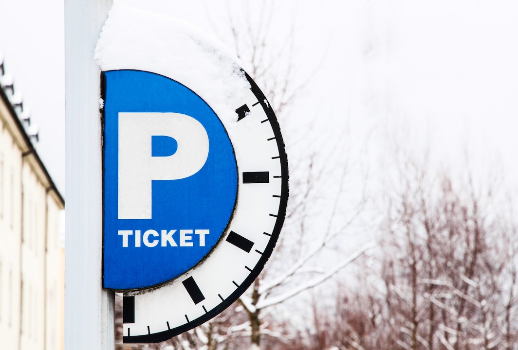 Blue parking sign with a capital P, with the inscription ticket and with a timeline on a snow background. Horizontal shot.