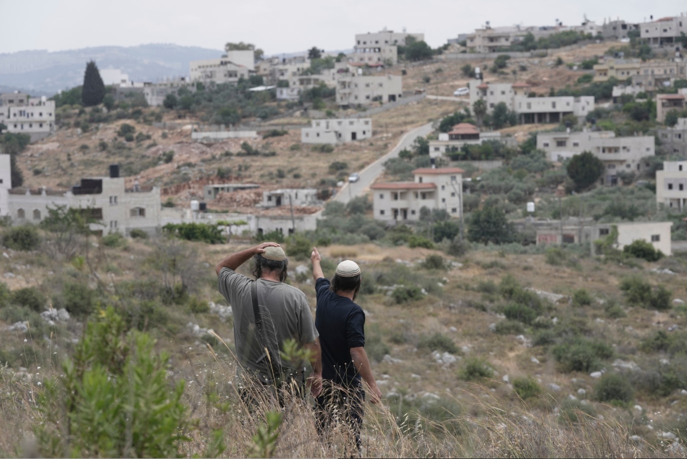 Israelische Siedler blicken auf ein Dorf im Westjordanland.