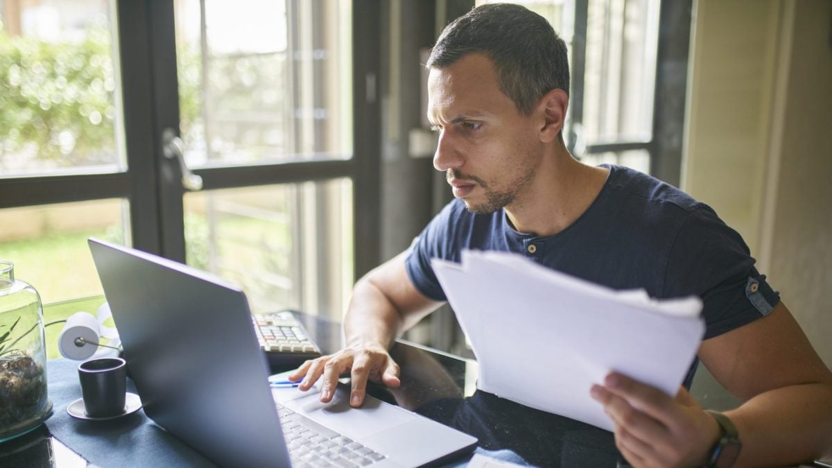 Mann sitzt am Rechner mit Dokumenten