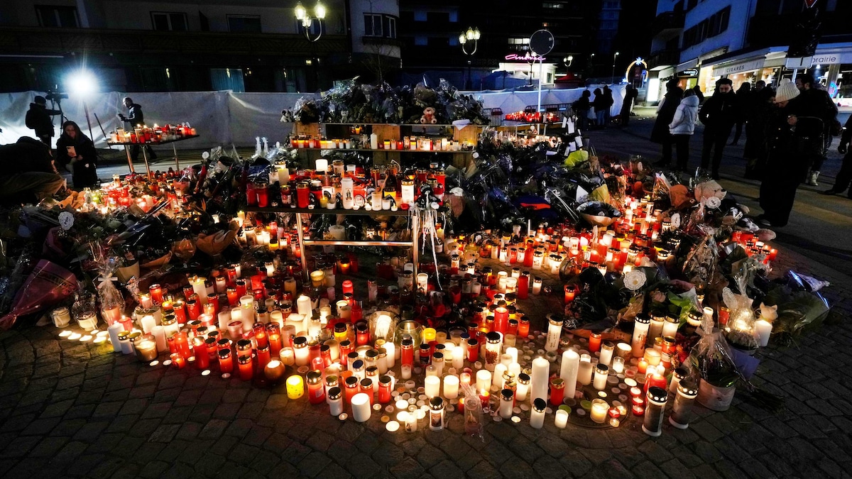 Menschen zünden Kerzen an und legen Blumen vor der versiegelten Bar Le Constellation in Crans-Montana.