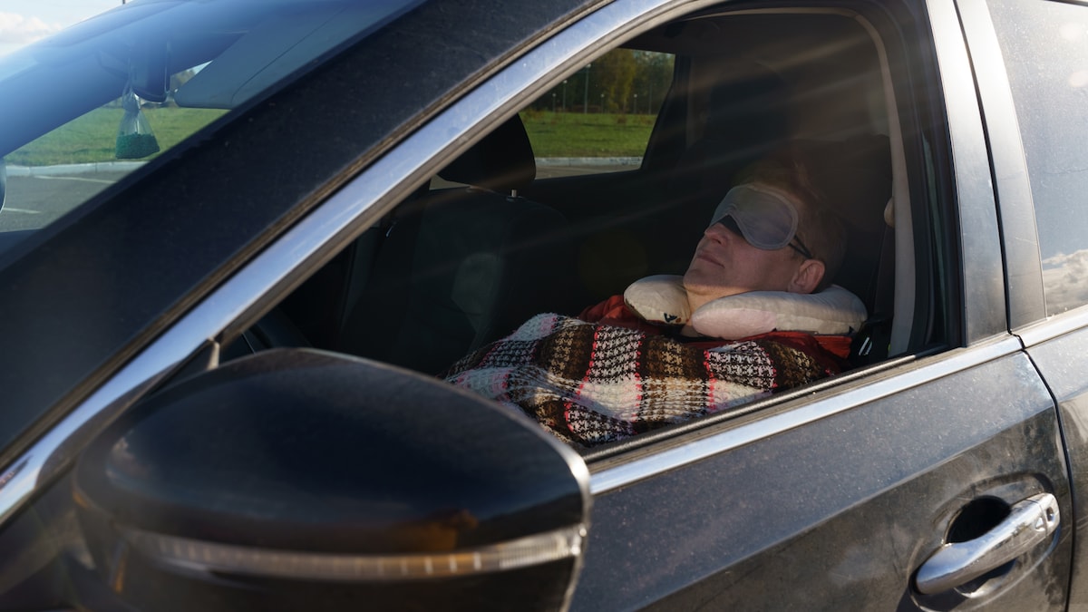 Mann schläft im Auto