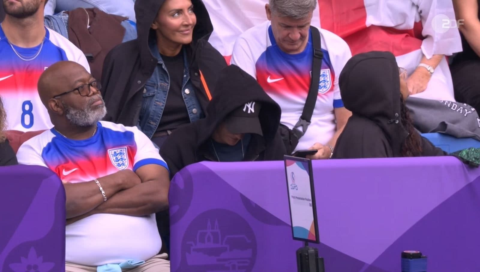 Ann-Katrin Berger sitzt mit Kappe und schwarzem Hoodie auf der Tribüne.