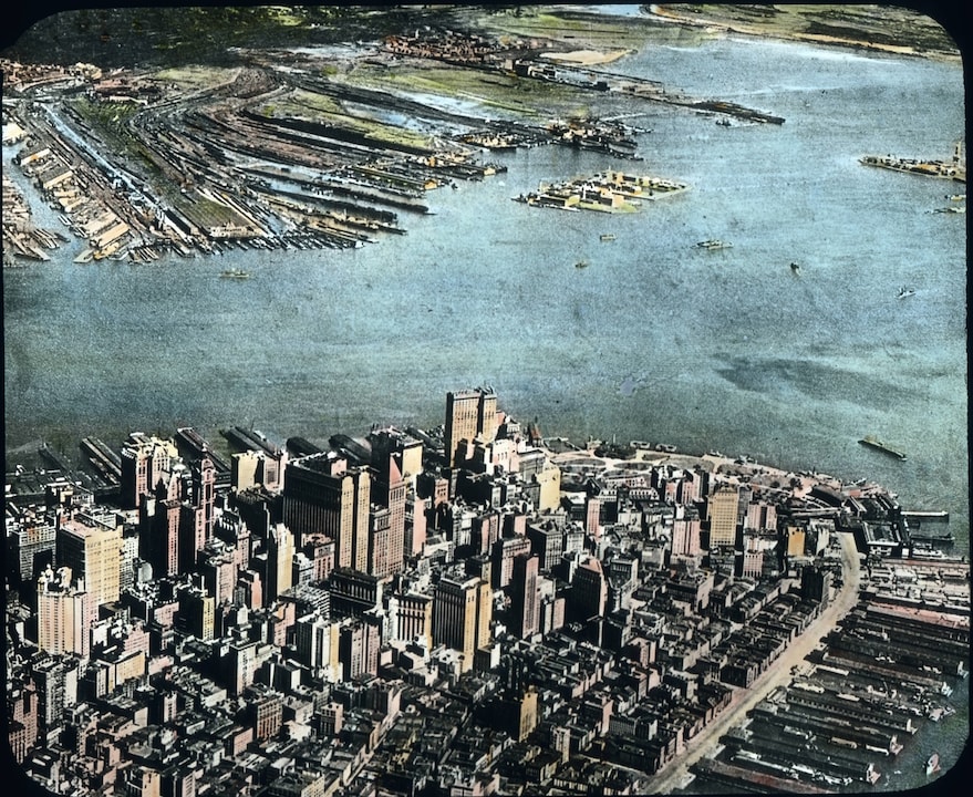 Por volta de 1910: Manhattan: Muitos navios de carga estão em frente à âncora. Dezenas de milhares de trabalhadores portuários às vezes passam algumas semanas de decepcionante e abaixando cada navio. Seus sistemas, armazéns e edifícios residenciais formam uma ilha como na parte inferior direita da imagem.