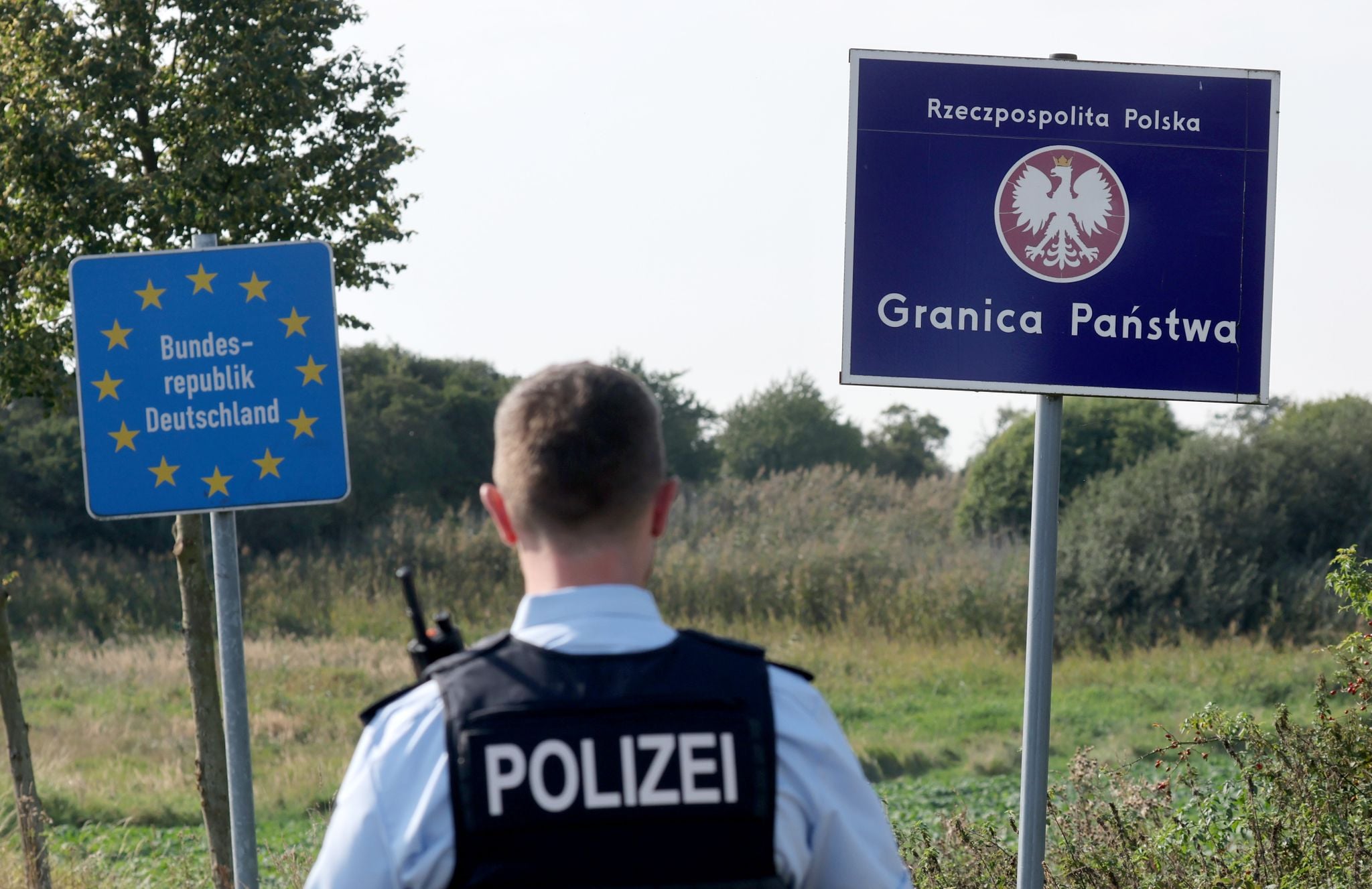 Bei einer flexiblen Schwerpunktkontrolle unmittelbar an der deutsch-polnischen Grenze in der Nähe des ehemaligen Grenzübergang Linken steht ein Bundespolizist vor den Schildern für Deutschland und Polen.