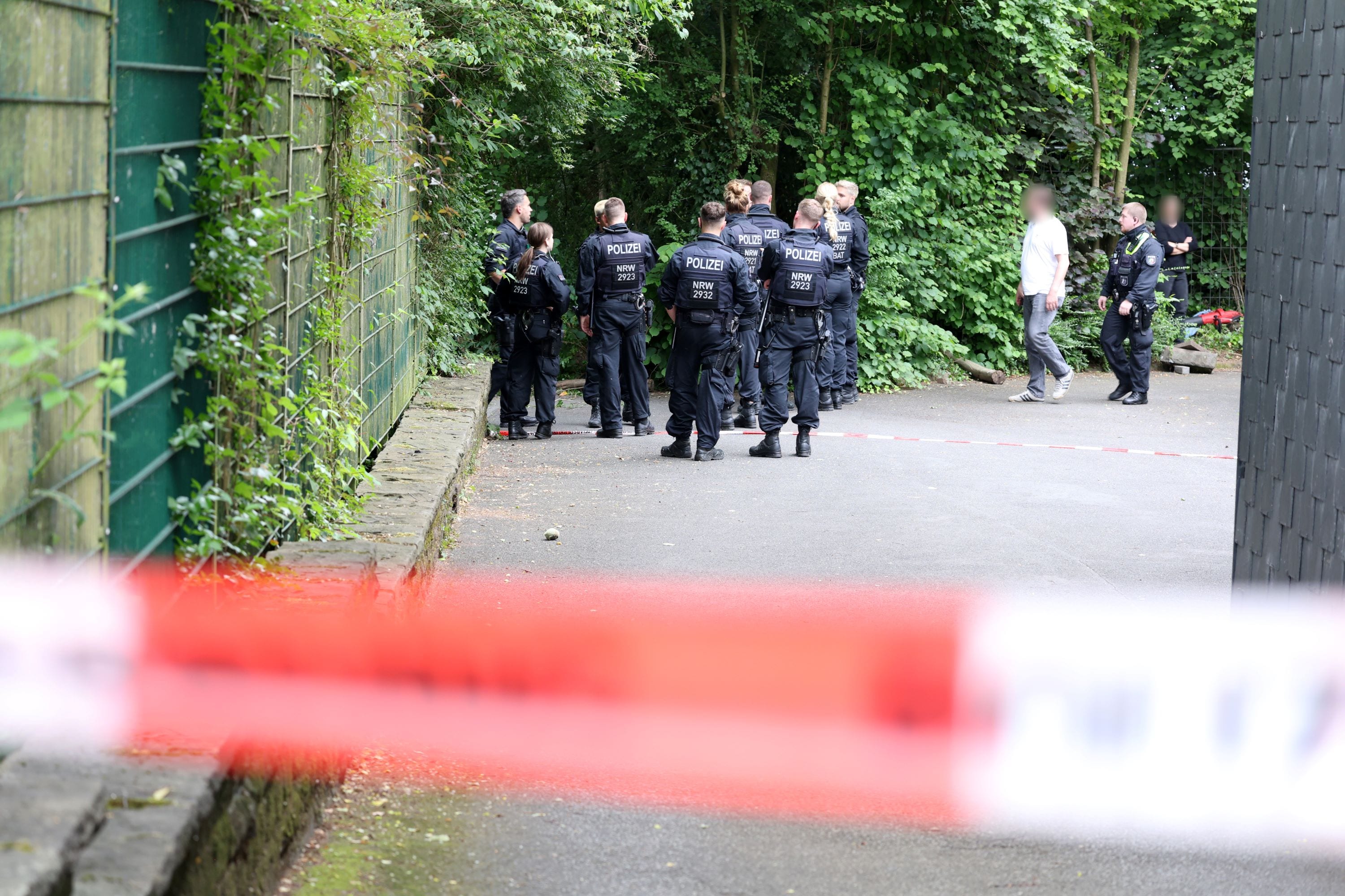 Solingen: Einsatzkräfte der Polizei stehen hinter einem Absperrband auf einem Grundstück