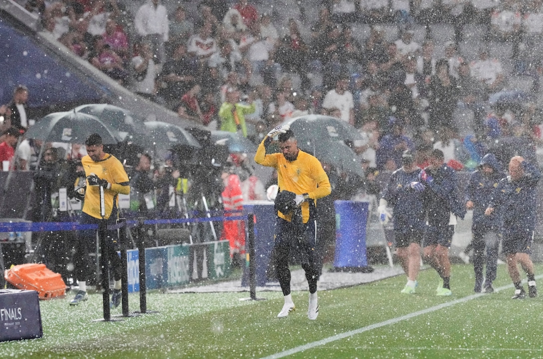 O goleiro português Diogo Costa (centro) sai correndo do campo durante uma tempestade de granizo antes da semifinal da Liga das Nações