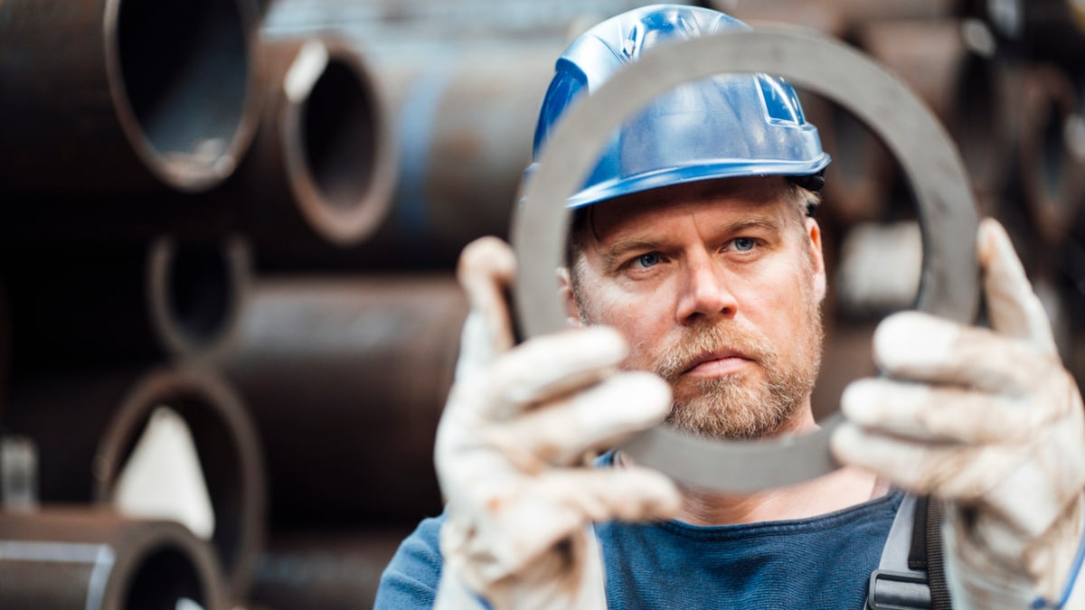 Männlicher Inspektor überprüft kreisförmige Stahlgeräte im Lager